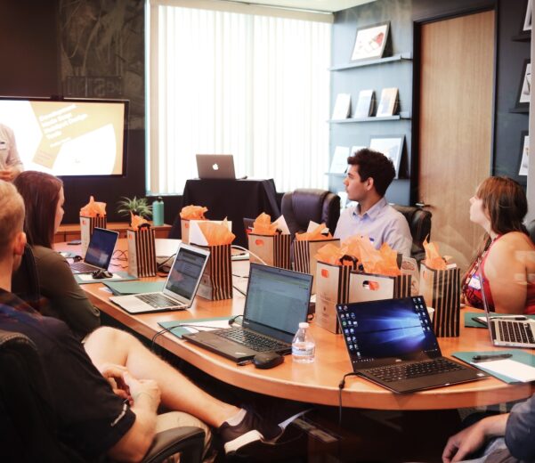 man standing in front of people sitting beside table with laptop computers